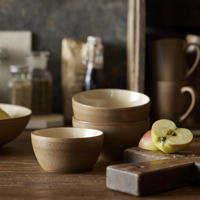 Set of ceramic bowls on a wooden surface with apples and a knife.