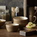 Set of ceramic bowls on a wooden surface with apples and a knife.