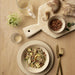 Table setting with a bowl of salad, bread, and almonds on a wooden table.