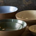 Set of ceramic bowls in various colors on a dark surface
