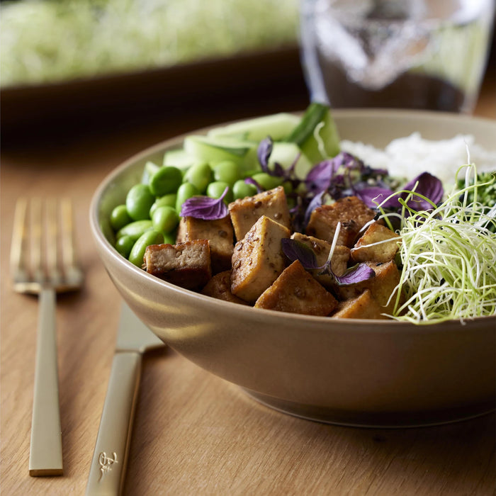 Bowl of salad with tofu and vegetables on a wooden table