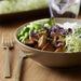 Bowl of salad with tofu and vegetables on a wooden table