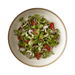Green salad with red peppers and onions in a white bowl on a white background