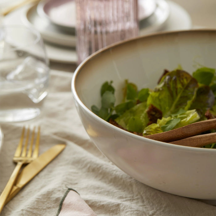 Bowl of salad on a table with cutlery and glasses