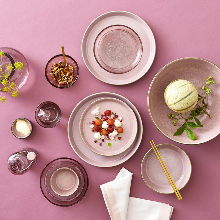 Table setting with pink plates, bowls, and chopsticks on a pink background