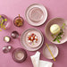 Table setting with pink plates, bowls, and chopsticks on a pink background