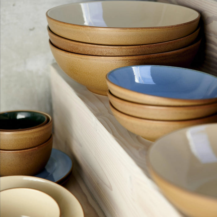 Stacks of ceramic bowls in various colors on a wooden surface.