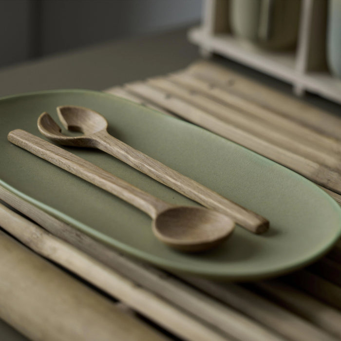 Wooden spoons on a green plate with a blurred background