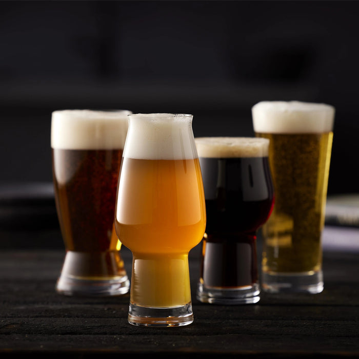 Four glasses of different types of beer on a dark surface with a blurred background