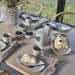 Table setting with ceramic teapot, cups, and plates with food on a wooden table.