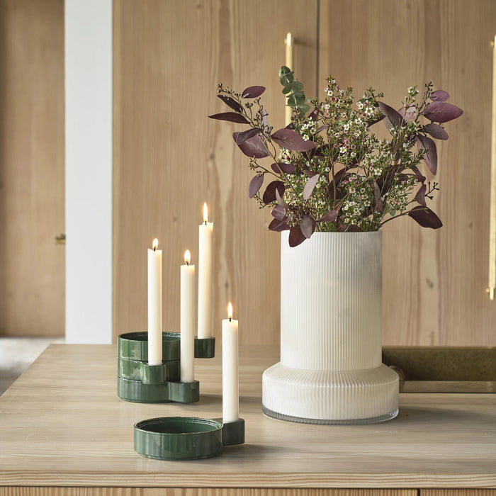 Decorative setup with a vase of flowers and candles on a wooden surface.