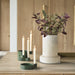 Decorative setup with a vase of flowers and candles on a wooden surface.