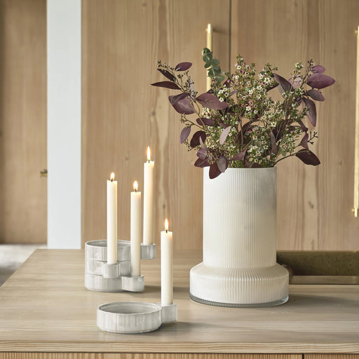 Decorative setup with a vase of flowers and candle holders on a wooden surface.