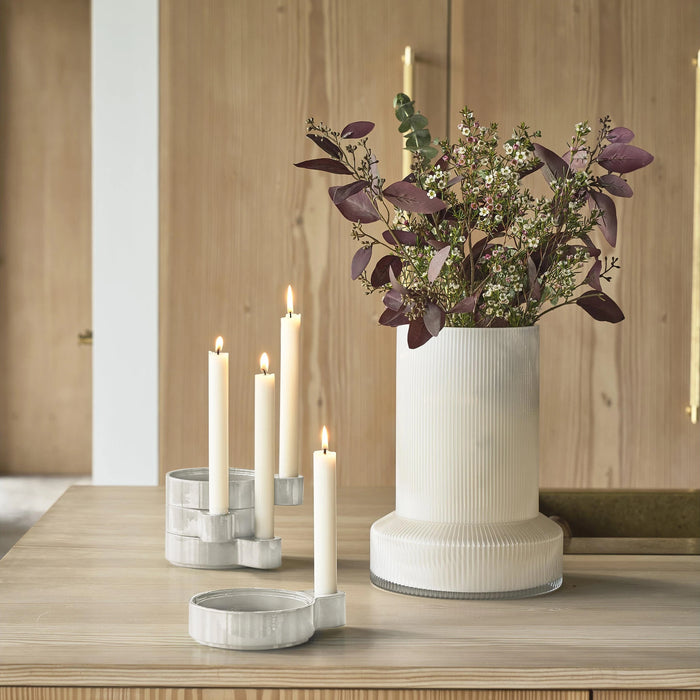 Decorative setup with a vase of flowers and candle holders on a wooden surface.