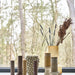 Decorative vases and candles on a windowsill with a blurred forest background