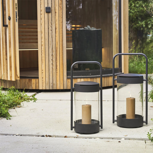 Black outdoor stools with candles in front of a wooden cabin.