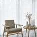 Modern armchair and side table with decorative vases in a minimalistic room.