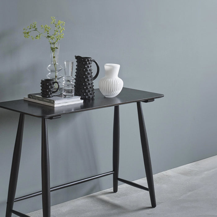 Black console table with decorative items against a gray wall