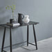 Black console table with decorative items against a gray wall