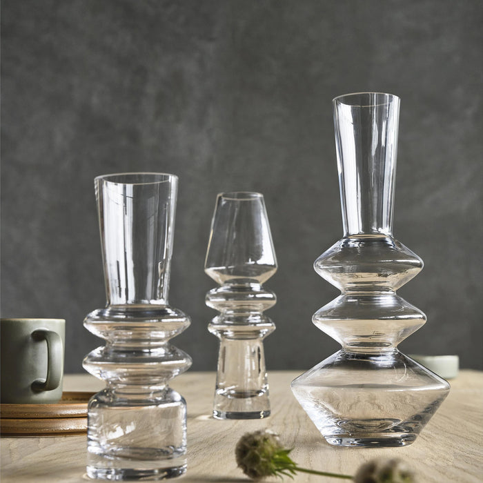 Set of clear glass candle holders on a wooden surface with a dark background