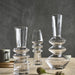 Set of clear glass candle holders on a wooden surface with a dark background