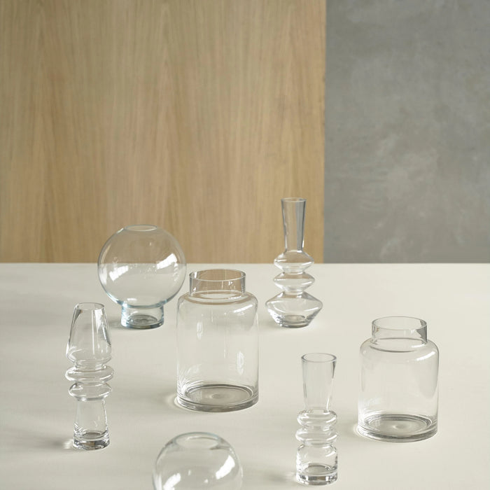 Set of clear glass vases on a white surface with a wooden and gray wall background