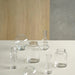 Set of clear glass vases on a white surface with a wooden and gray wall background