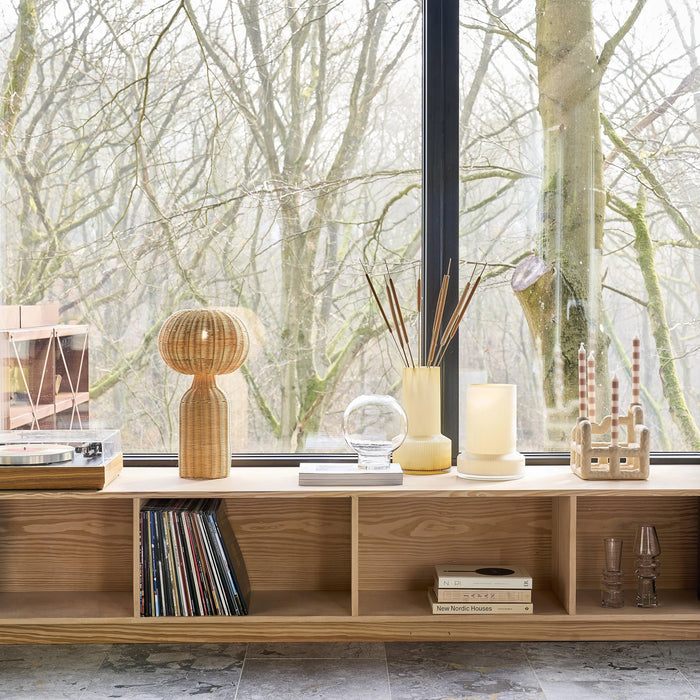 Wooden shelf with decorative items against a window with bare trees outside