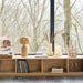 Wooden shelf with decorative items against a window with bare trees outside