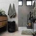 Bathroom interior with towels hanging, a black laundry basket, and a shower area.
