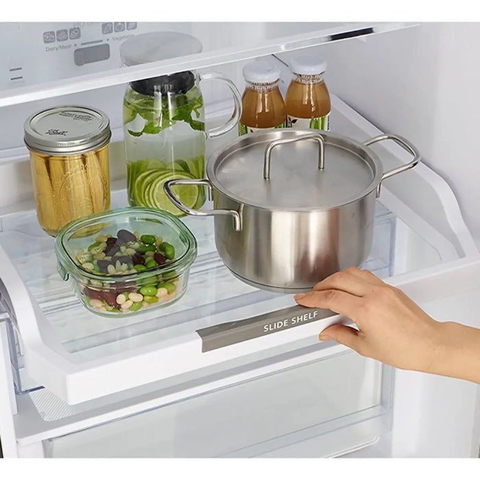 Stainless steel pot on a slide-out shelf in an open refrigerator.