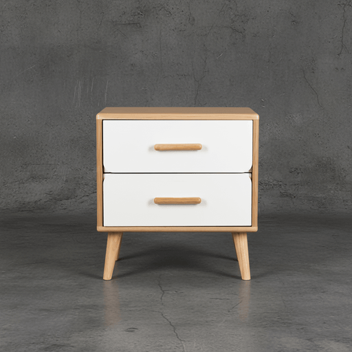 Wooden nightstand with two white drawers and wooden handles against a gray concrete wall.