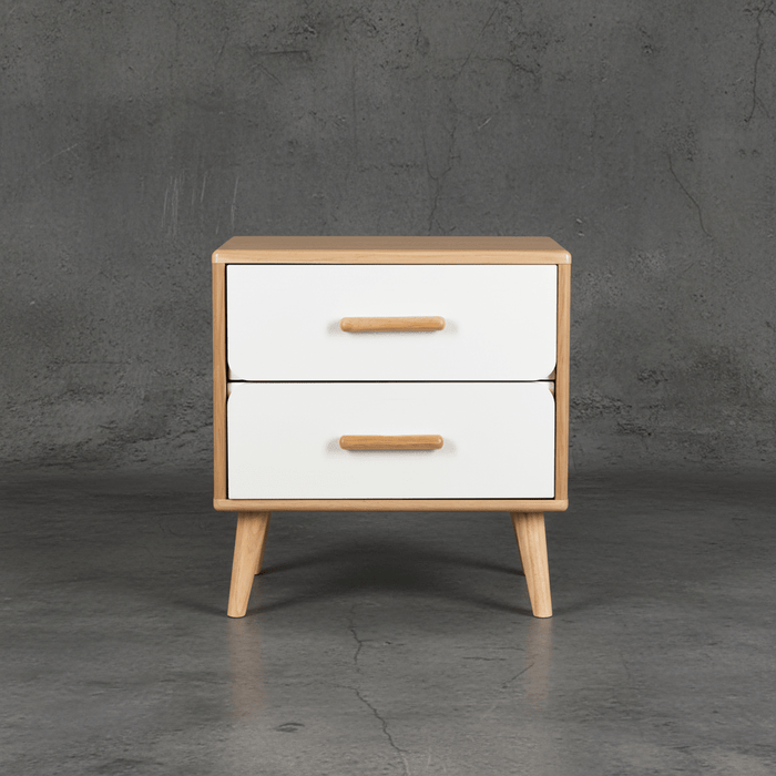 Wooden nightstand with two white drawers and wooden handles against a gray concrete wall.