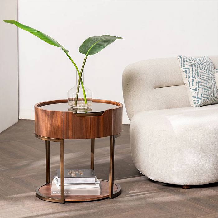 Wooden side table with a plant and books next to a beige armchair.