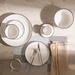 Dining table setting with white ceramic plates, cutlery, and a folded napkin on a textured surface.