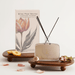 Reed diffuser with packaging and decorative elements on a light background
