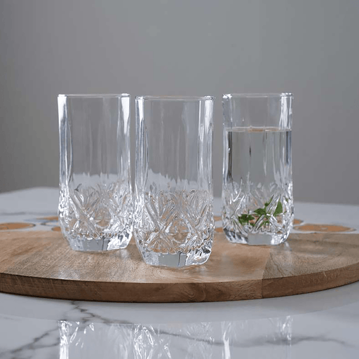 Three crystal glasses on a wooden board with a gray background