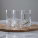 Three crystal glasses on a wooden board with a gray background