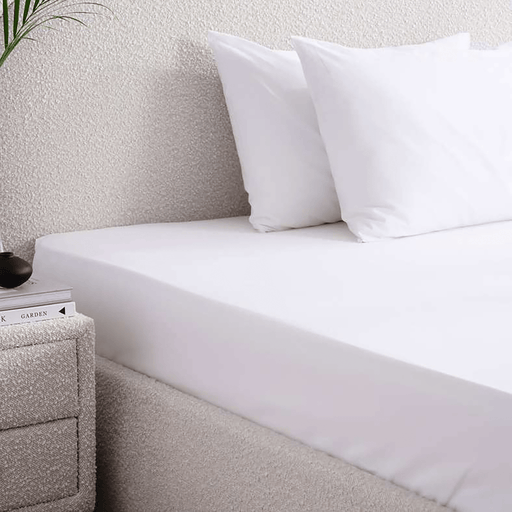 Bed with white bedding and pillows in a bedroom setting.