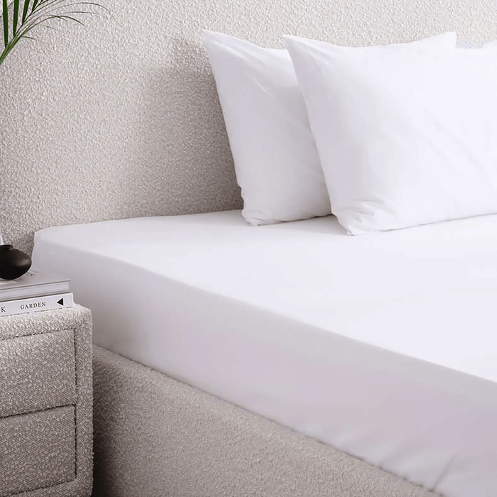 Bed with white bedding and pillows in a bedroom setting.