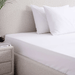 Bed with white bedding and pillows in a bedroom setting.