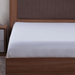 Bed with wooden frame and white fitted sheet in a bedroom setting