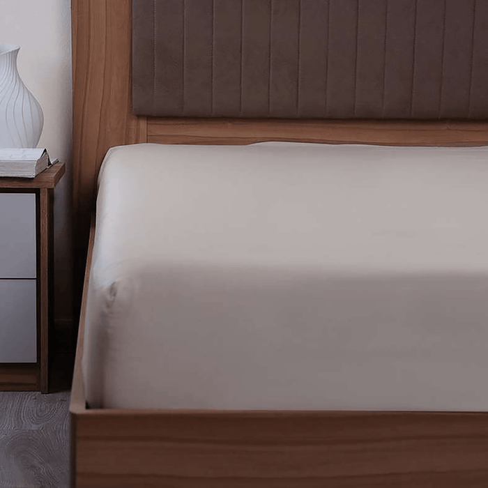 Bed with wooden headboard and nightstand in a bedroom setting