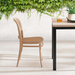 Wooden chair and table with a white wall and greenery in the background