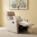 A beige upholstered recliner chair with the footrest extended, styled with a matching accent pillow and a cream throw blanket. The chair is set on a textured beige rug against a warm yellow wall, with a framed tree painting hanging above.