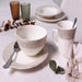 Ceramic tableware set with cups, bowls, and plates on a light surface.