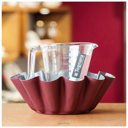 Red measuring cup holder with a clear measuring cup inside, on a wooden surface.