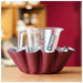Red measuring cup holder with a clear measuring cup inside, on a wooden surface.