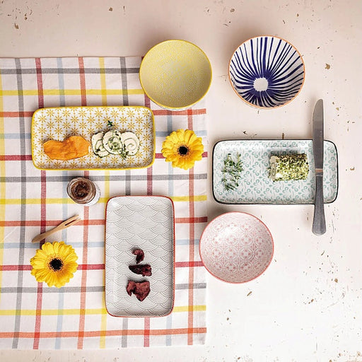 Table setting with ceramic plates, bowls, and a checkered tablecloth.