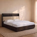 A modern platform bed with a dark wood frame and a beige upholstered headboard, styled with white bedding and pillows in a warm, minimalist bedroom setting.